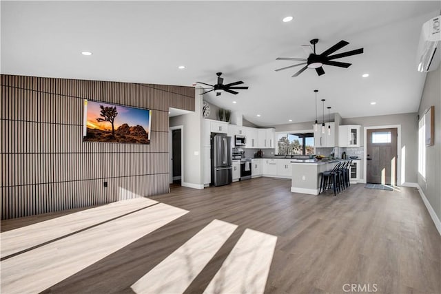 unfurnished living room with ceiling fan, a wall mounted AC, dark wood-type flooring, and vaulted ceiling