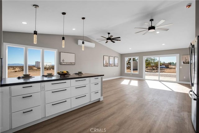 kitchen with hanging light fixtures, vaulted ceiling, dark hardwood / wood-style floors, and white cabinetry