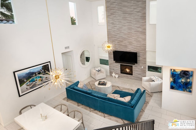 living room featuring light tile patterned floors, a tile fireplace, and a notable chandelier