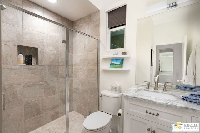 bathroom featuring toilet, vanity, and a shower with shower door