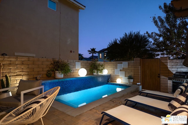 pool at dusk featuring grilling area