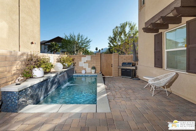 view of pool with pool water feature and grilling area