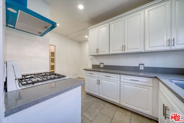 kitchen featuring white cabinetry, stainless steel gas stovetop, and extractor fan