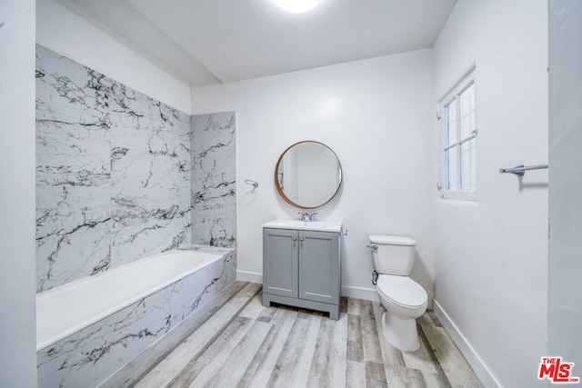 bathroom with hardwood / wood-style flooring, tiled tub, toilet, and vanity