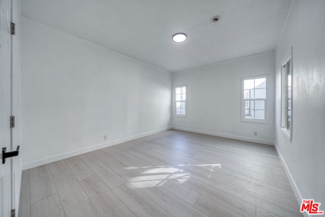 empty room with light hardwood / wood-style floors, plenty of natural light, and ornamental molding