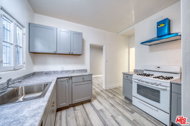 kitchen featuring gray cabinetry, white gas range, light hardwood / wood-style flooring, and sink