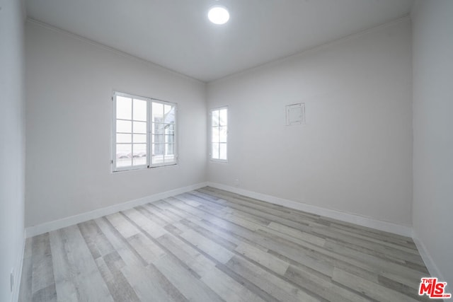 empty room with light hardwood / wood-style floors and ornamental molding