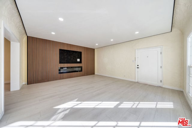 unfurnished living room with wood walls and light hardwood / wood-style flooring