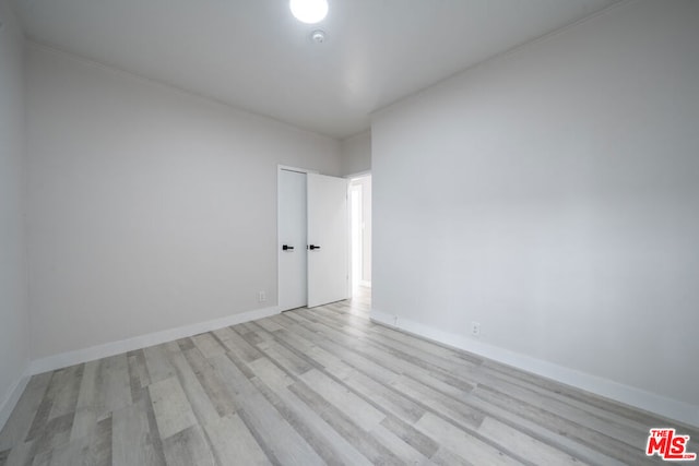 spare room featuring ornamental molding and light hardwood / wood-style floors