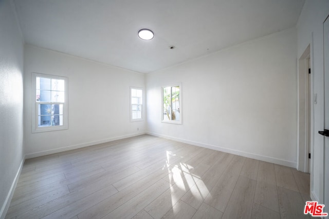 spare room with ornamental molding and light hardwood / wood-style floors