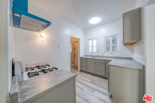 kitchen featuring range with gas cooktop, exhaust hood, sink, light hardwood / wood-style flooring, and gray cabinetry