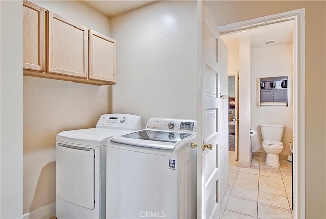 laundry area with cabinets, light tile patterned floors, and washing machine and clothes dryer