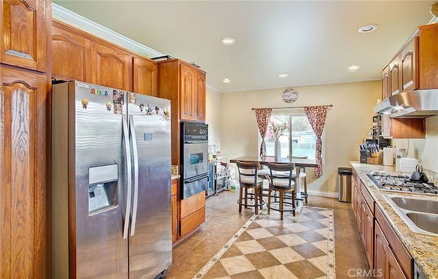 kitchen featuring light stone counters, sink, crown molding, and appliances with stainless steel finishes