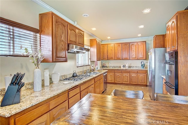 kitchen featuring stainless steel appliances, ornamental molding, light stone countertops, and sink