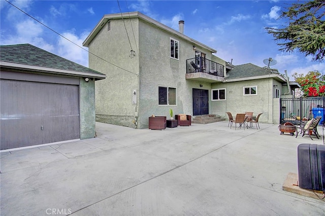 rear view of house featuring a fire pit, a garage, a patio area, and a balcony