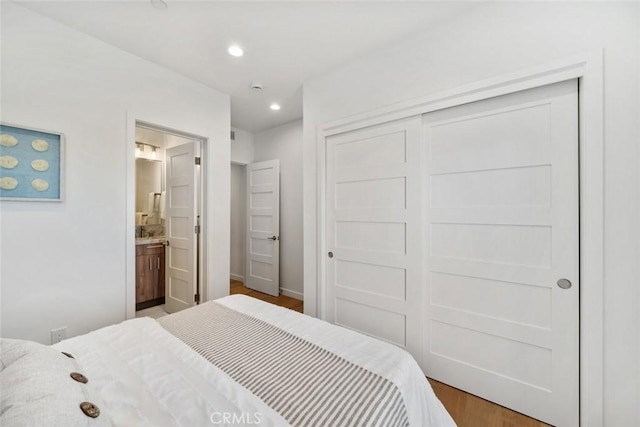 bedroom featuring hardwood / wood-style flooring, ensuite bathroom, and a closet