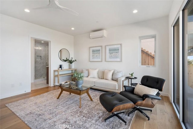 living room with light wood-type flooring, ceiling fan, and a wall mounted air conditioner