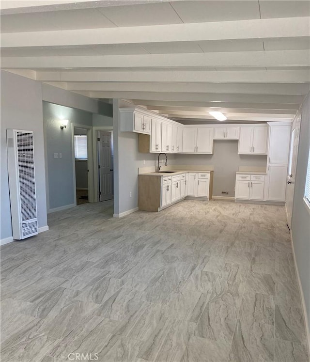 kitchen featuring white cabinets, sink, and beamed ceiling