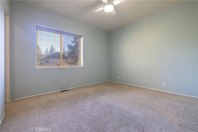 carpeted empty room featuring baseboards, visible vents, and a ceiling fan