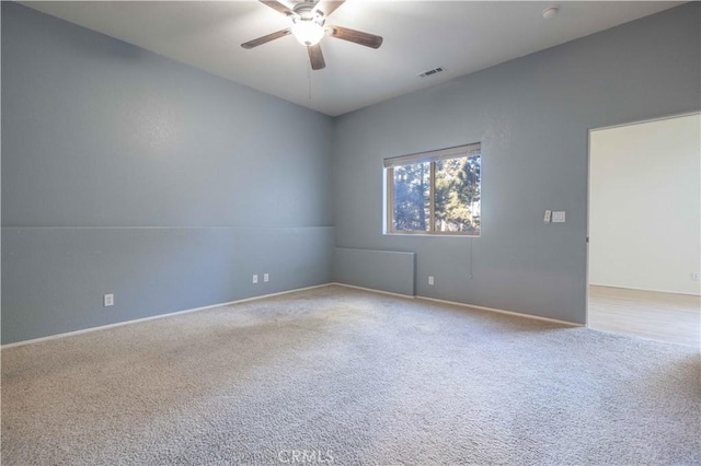 spare room featuring carpet floors, ceiling fan, and visible vents