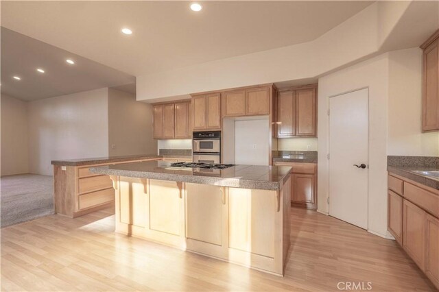 kitchen with stainless steel appliances, an island with sink, a breakfast bar, and light wood-type flooring