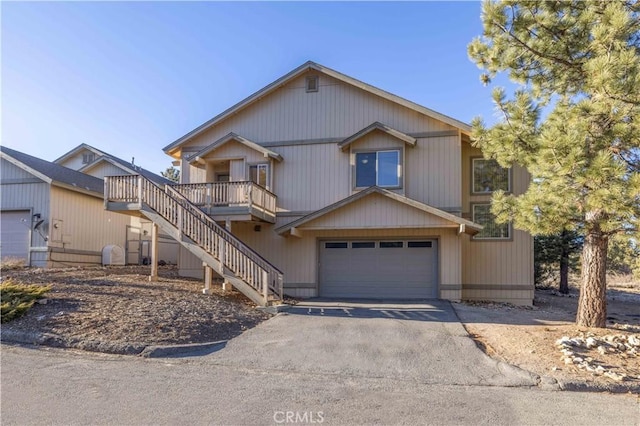 view of front of property with driveway, an attached garage, and stairs