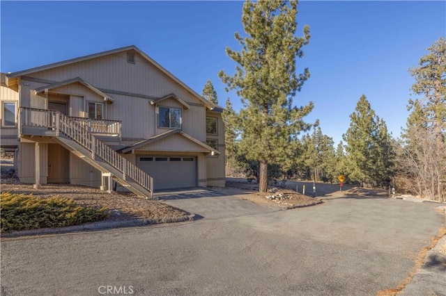 view of front of home featuring driveway, an attached garage, and stairs