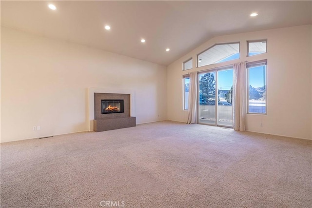 unfurnished living room featuring lofted ceiling, a glass covered fireplace, light carpet, and recessed lighting