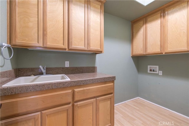 laundry area with washer hookup, cabinet space, a sink, and light wood finished floors