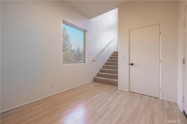 interior space featuring light wood-style flooring, stairway, and baseboards