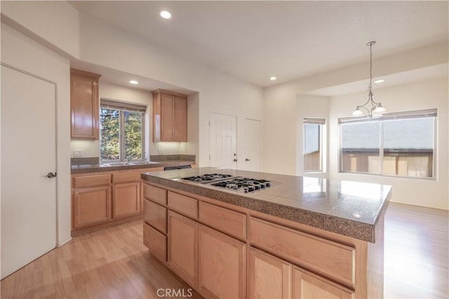 kitchen with tile counters, stainless steel gas stovetop, light wood finished floors, and light brown cabinetry