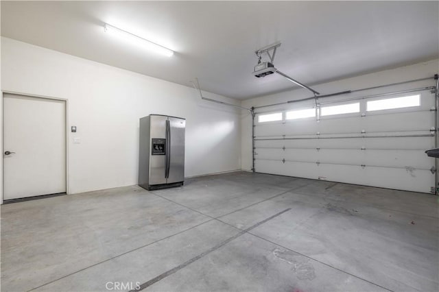 garage with a garage door opener and stainless steel fridge