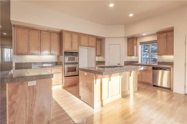 kitchen with stainless steel appliances, recessed lighting, light wood-style floors, and a breakfast bar area