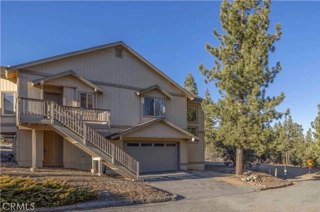 view of front of home with driveway, an attached garage, and stairs