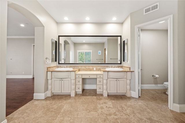 bathroom with toilet, crown molding, and vanity