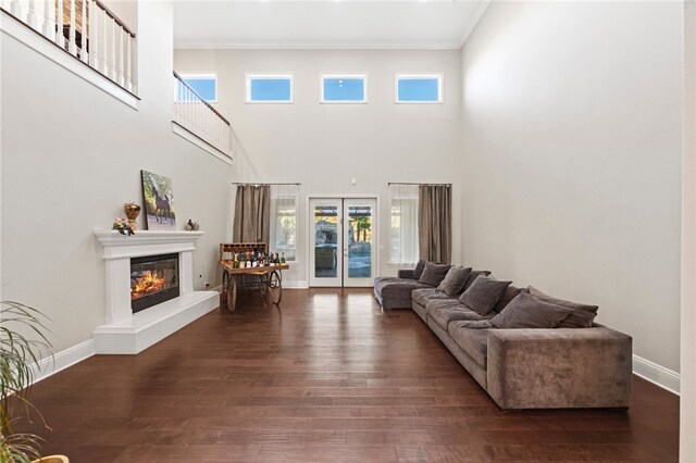 living room with french doors, dark hardwood / wood-style floors, crown molding, and a towering ceiling