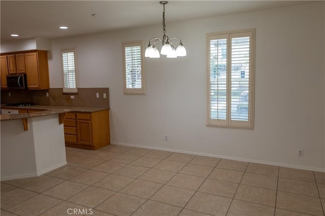 kitchen with decorative light fixtures, decorative backsplash, a notable chandelier, light tile patterned flooring, and a breakfast bar