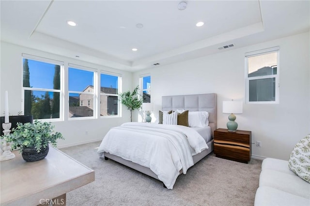 bedroom with light carpet and a raised ceiling