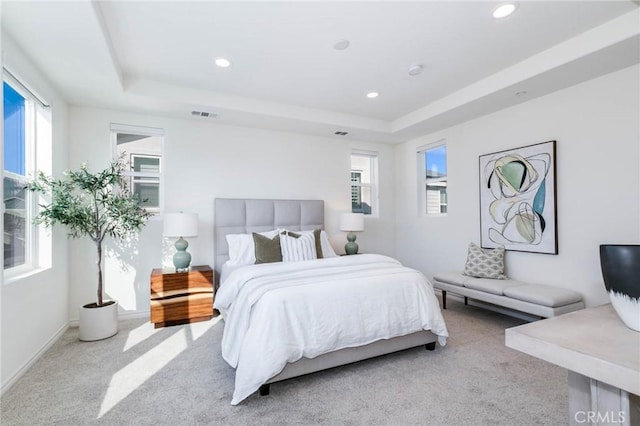 bedroom with a raised ceiling and light colored carpet