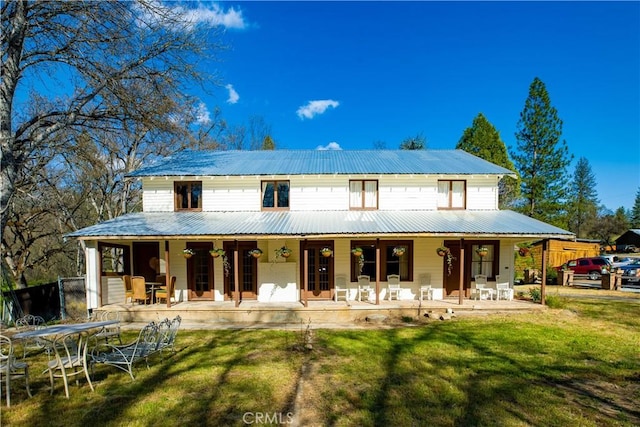 back of property with covered porch, metal roof, and a yard