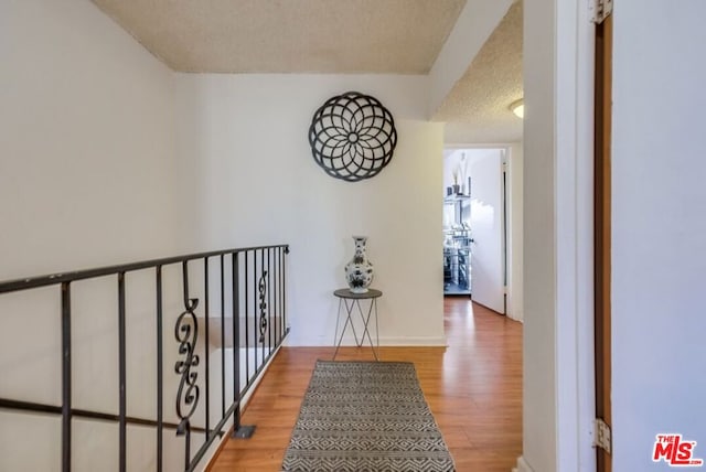 corridor featuring wood-type flooring and a textured ceiling