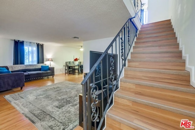 stairway featuring a textured ceiling and hardwood / wood-style flooring