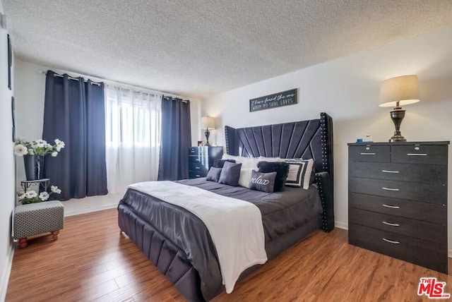 bedroom with hardwood / wood-style flooring and a textured ceiling