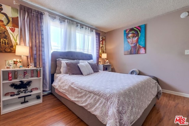 bedroom with a textured ceiling and hardwood / wood-style floors