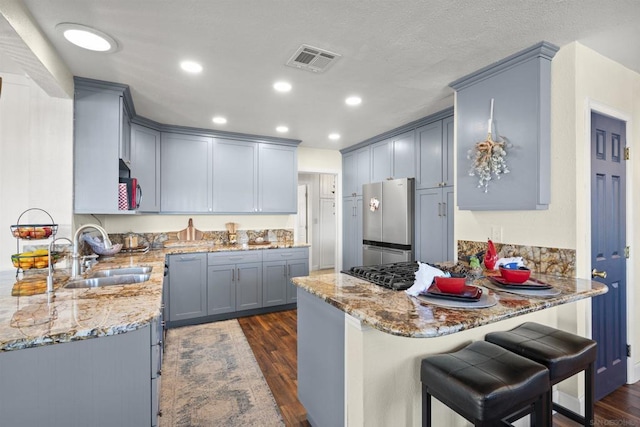 kitchen featuring light stone countertops, sink, stainless steel appliances, and kitchen peninsula