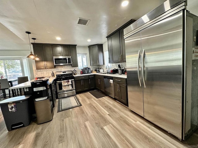 kitchen featuring hanging light fixtures, light wood-type flooring, plenty of natural light, and stainless steel appliances