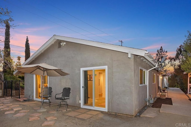 back house at dusk featuring a patio area