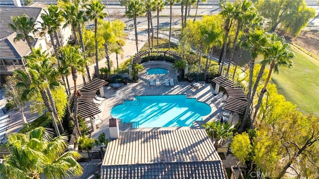 pool with a patio area, glass enclosure, and a community hot tub