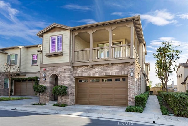 townhome / multi-family property with a balcony, brick siding, concrete driveway, and a garage