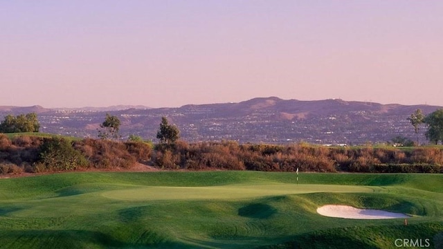 view of property's community with a mountain view, a yard, and view of golf course